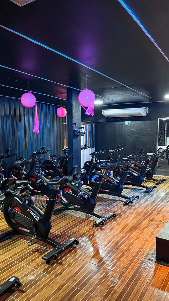 Vista ampla da sala de bike indoor da Performance, climatizada e com piso de madeira